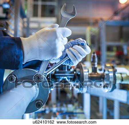 Stock Image - Close up engineers hands tightening pipework with spanners in power station. Fotosearch