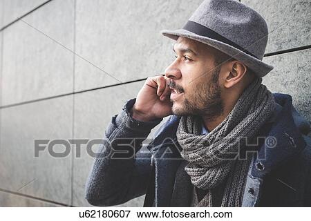 Close up of businessman leaning against wall talking on smartphone View Large Photo Image Stock Photo - Close up of businessman leaning against wall talking on smartphone. Fotosearch