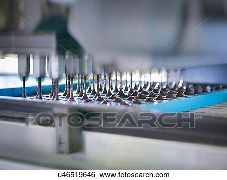 Stock Photograph - Close up of chocolate pouring into moulds in chocolate factory. Fotosearch
