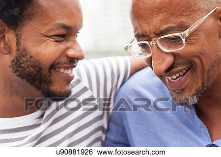 Stock Photograph - "Close up of father and mid adult son on Ipanema Beach, Rio De Janeiro, Brazil". Fotosearch