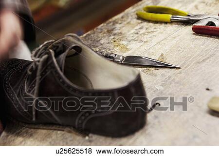 Stock Photo - Close up of leather brogue and hand tools in shoe makers workshop. Fotosearch