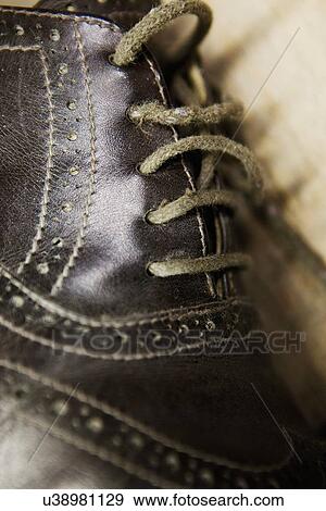 Stock Photo - Close up of leather brogue and shoelaces in shoe makers workshop. Fotosearch