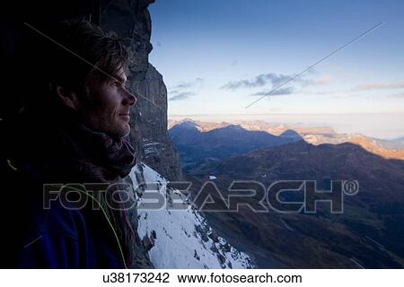 Stock Image - "Close up of male hiker gazing at view, Jungfraujoch, Grindelwald, Switzerland". Fotosearch