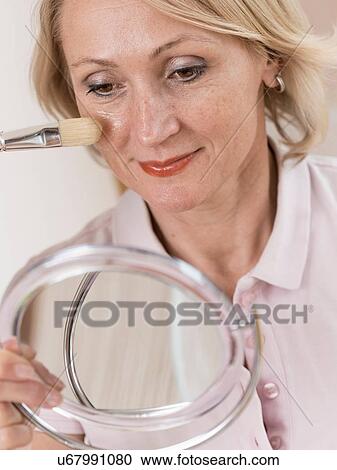 Close up of mature woman looking in hand mirror applying blusher View Large Photo Image Stock Image - Close up of mature woman looking in hand mirror applying blusher. Fotosearch