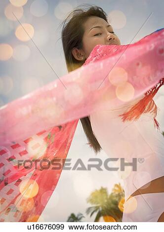 Stock Photo - "Close up of mid adult woman holding up pink scarf, Ari Atoll, Maldives". Fotosearch