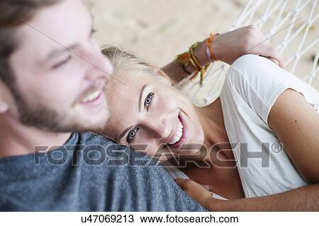 Close up of smiling young couple on beach hammock View Large Photo Image Stock Image - Close up of smiling young couple on beach hammock. Fotosearch