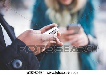 "Close up of two young women texting on smartphones, Lake Como, Como, Italy" View Large Photo Image Picture - "Close up of two young women texting on smartphones, Lake Como, Como, Italy". Fotosearch