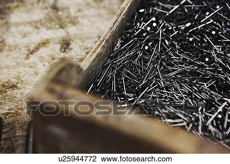 Stock Image - Close up of wooden nail box on bench in shoe makers workshop. Fotosearch