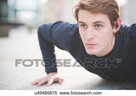Stock Photography - Close up of young man doing press ups in city square. Fotosearch
