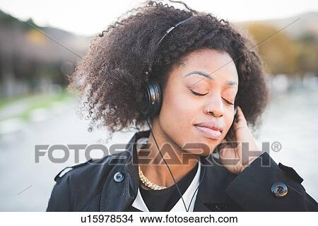"Close up of young woman listening to headphones with eyes closed at Lake Como, Italy" View Large Photo Image Picture - "Close up of young woman listening to headphones with eyes closed at Lake Como, Italy". Fotosearch