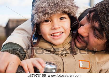 Stock Photograph - Close up portrait of mid adult man and son on bicycle. Fotosearch