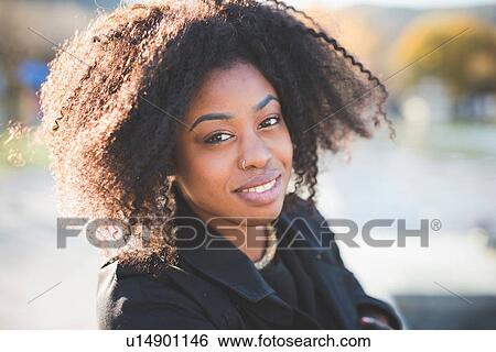 Stock Photograph - Close up portrait of smiling young woman in park. Fotosearch