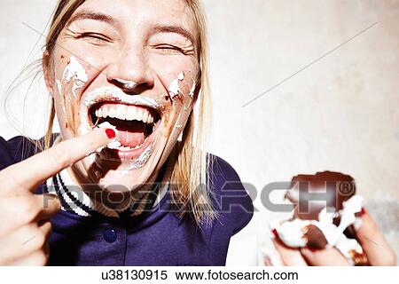 Stock Photography - Close up studio shot of young woman with face covered in chocolate marshmallow. Fotosearch