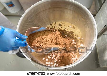 Stock Image - "Cocoa powder being poured into cake mix in cake factory, close up". Fotosearch