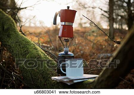 Stock Image - Coffee pot on camping stove in woods. Fotosearch