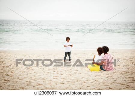 Stock Photo - Couple and son taking photograph on beach. Fotosearch