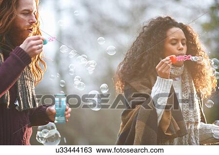 Couple blowing soap bubbles in countryside View Large Photo Image Stock Image - Couple blowing soap bubbles in countryside. Fotosearch