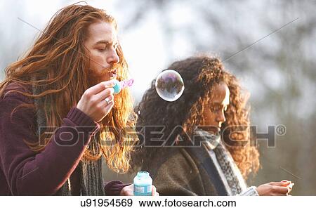 Couple blowing soap bubbles in countryside View Large Photo Image Stock Photo - Couple blowing soap bubbles in countryside. Fotosearch