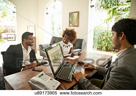 Stock Photography - Couple checking in at hotel reception desk. Fotosearch