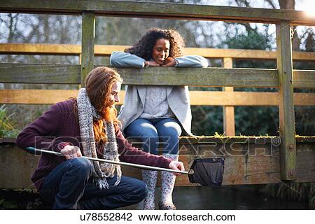 Stock Image - Couple fishing on bridge in countryside. Fotosearch