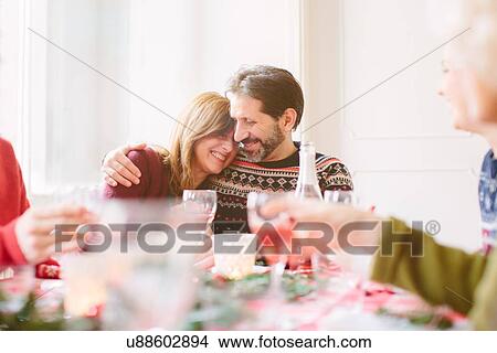 Picture - Couple hugging at family Christmas party. Fotosearch