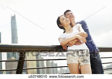 Stock Image - "Couple hugging on the waterfront, The Bund, Shanghai, China". Fotosearch
