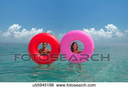 Couple looking through inflatable rings in sea View Large Photo Image Stock Photo - Couple looking through inflatable rings in sea. Fotosearch