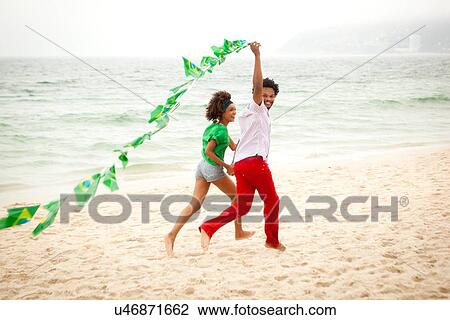 "Couple playing with string of flags on beach, Rio de Janeiro, Brazil" View Large Photo Image Stock Image - "Couple playing with string of flags on beach, Rio de Janeiro, Brazil". Fotosearch