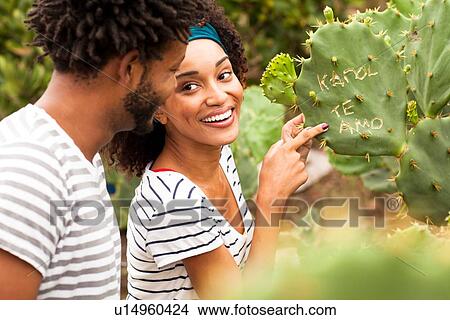 Picture - "Couple pointing at graffiti on cacti leaf on Ipanema Beach, Rio De Janeiro, Brazil". Fotosearch