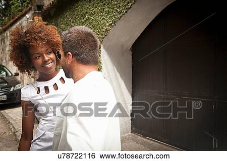 Stock Photograph - Couple standing by garage door. Fotosearch