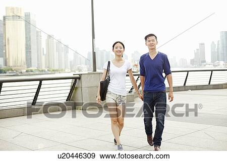 Stock Photo - "Couple strolling hand in hand on the waterfront, The Bund, Shanghai, China". Fotosearch