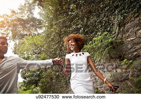 Stock Image - "Couple walking on street, holding hands". Fotosearch