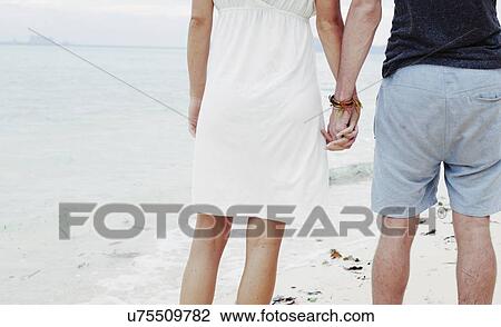 "Cropped rear view of young couple holding hands on beach, Kradan, Thailand" View Large Photo Image Stock Image - "Cropped rear view of young couple holding hands on beach, Kradan, Thailand". Fotosearch