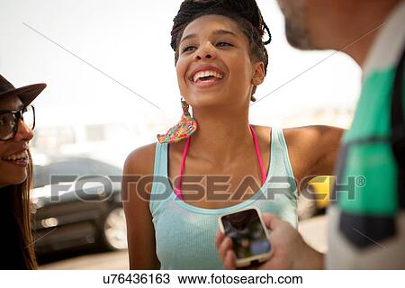 Stock Image - "Cropped shot of adult friends chatting on sidewalk, Copacabana, Rio De Janeiro, Brazil". Fotosearch