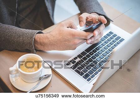 Cropped shot of businessman sitting in cafe texting on smartphone View Large Photo Image Stock Photo - Cropped shot of businessman sitting in cafe texting on smartphone. Fotosearch