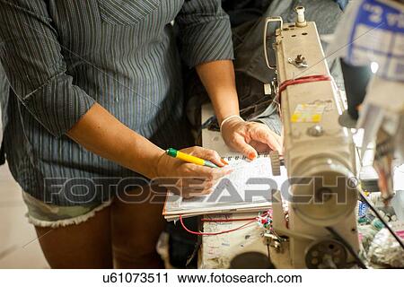 Stock Image - Cropped shot of seamstresses making notes in sewing workshop. Fotosearch