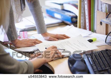 Cropped shot of two businesswomen checking paperwork at office desk View Large Photo Image Stock Image - Cropped shot of two businesswomen checking paperwork at office desk. Fotosearch
