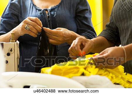 Stock Photo - Cropped shot of two seamstresses sewing in workshop. Fotosearch