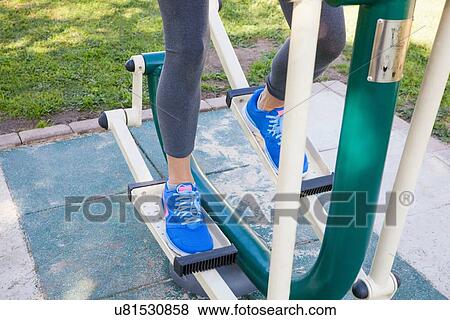 Stock Photo - Cropped shot of womans legs training on step machine in park. Fotosearch