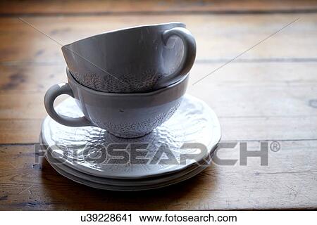 Stock Image - Cups and saucers on wooden table. Fotosearch