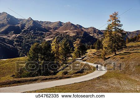 Stock Photography - "Cyclist on road with mountains in distance, Valais, Switzerland". Fotosearch