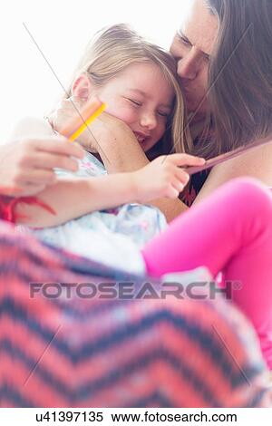 Stock Photography - "Daughter sitting on mother's lap, laughing". Fotosearch