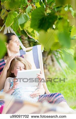 Daughter sitting on mother's lap using digital tablet View Large Photo Image Stock Image - Daughter sitting on mother's lap using digital tablet. Fotosearch
