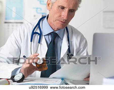 Doctor checking medical notes before prescribing drugs View Large Photo Image Stock Photo - Doctor checking medical notes before prescribing drugs. Fotosearch