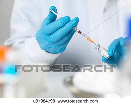 Doctor preparing a vaccine to inject into a patient View Large Photo Image Stock Photo - Doctor preparing a vaccine to inject into a patient. Fotosearch