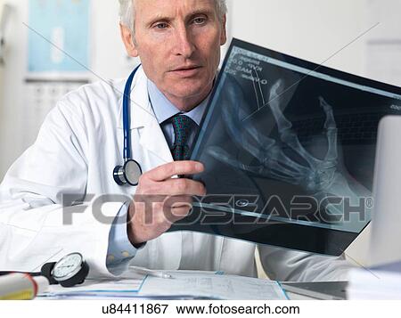 Doctor viewing x-ray of hand in clinic View Large Photo Image Stock Photo - Doctor viewing x-ray of hand in clinic. Fotosearch