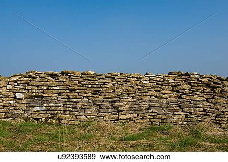 Stock Photo - Edge of field and traditional Cotswold dry limestone wall. Fotosearch