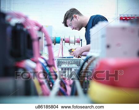 Electrical engineer assembling switch board in engineering factory View Large Photo Image Picture - Electrical engineer assembling switch board in engineering factory. Fotosearch
