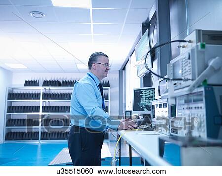 Stock Image - Electromagnetic compatibility engineer carrying out radiated emissions scan on electrical equipment in anechoic chamber using high performance power supply and network analyser. Fotosearch