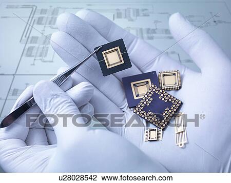 Stock Image - "Electronic components held in hand in laboratory, close up". Fotosearch